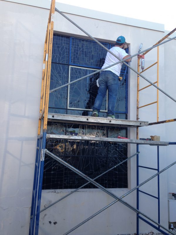 The restored Jesus window gets re-installed- note the improvement to the old framing which has been sanded and repainted